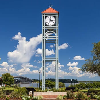 Clock tower in center of downtown Palatka, FL with bridge and water in distance