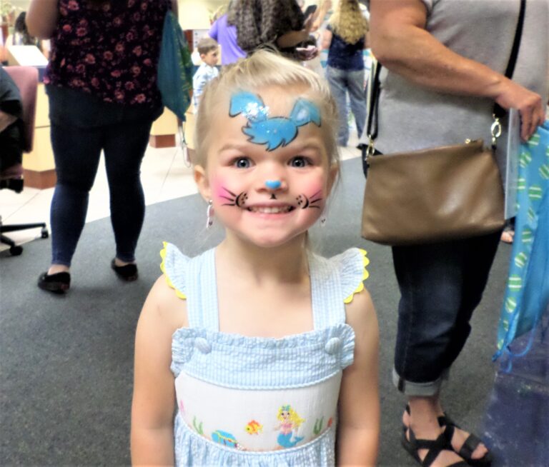 Young girl with bunny face paint smiling for camera