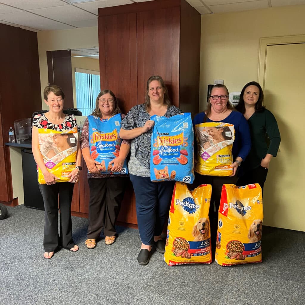 Group of women holding bags of cat food