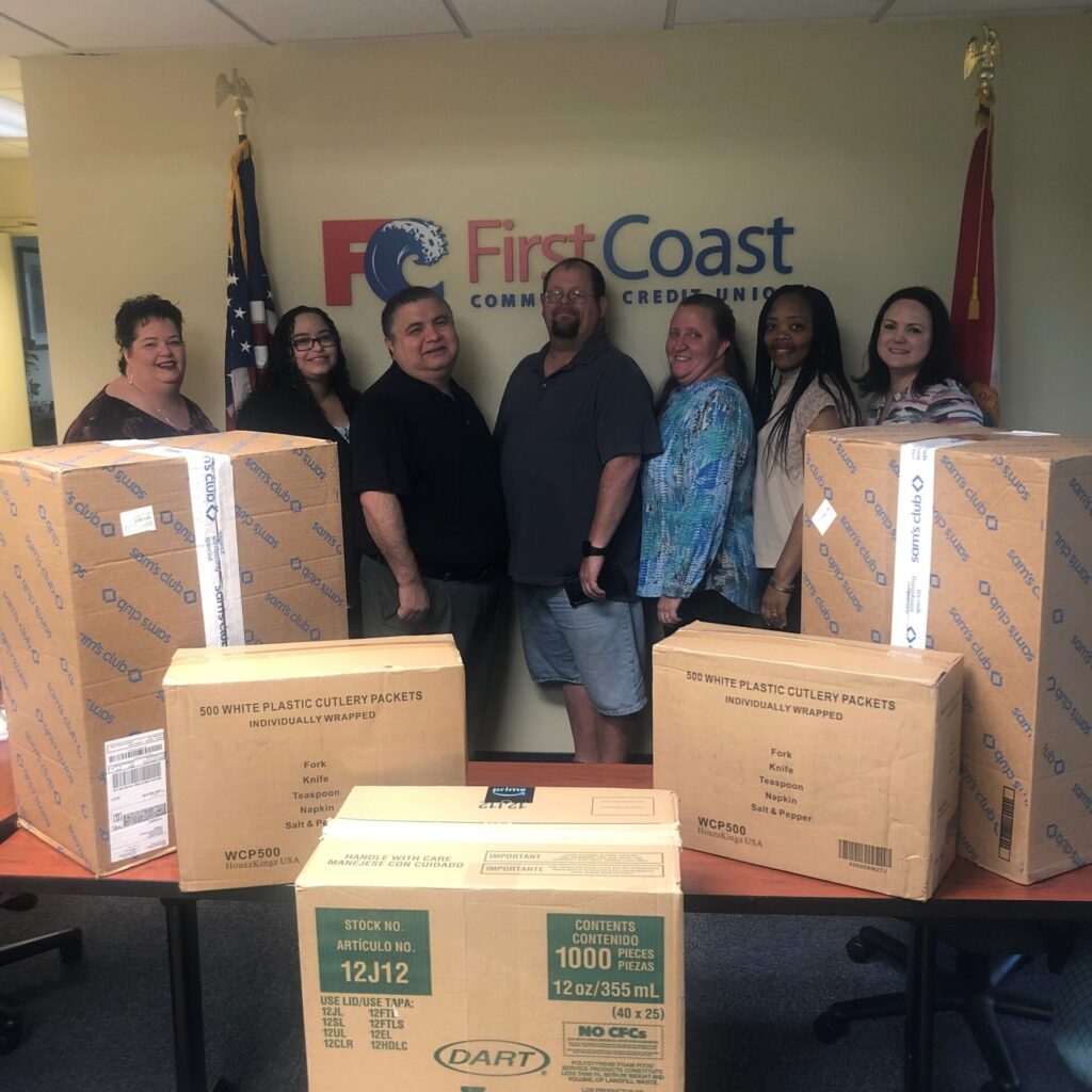 Group of people standing behind table with large boxes in foreground