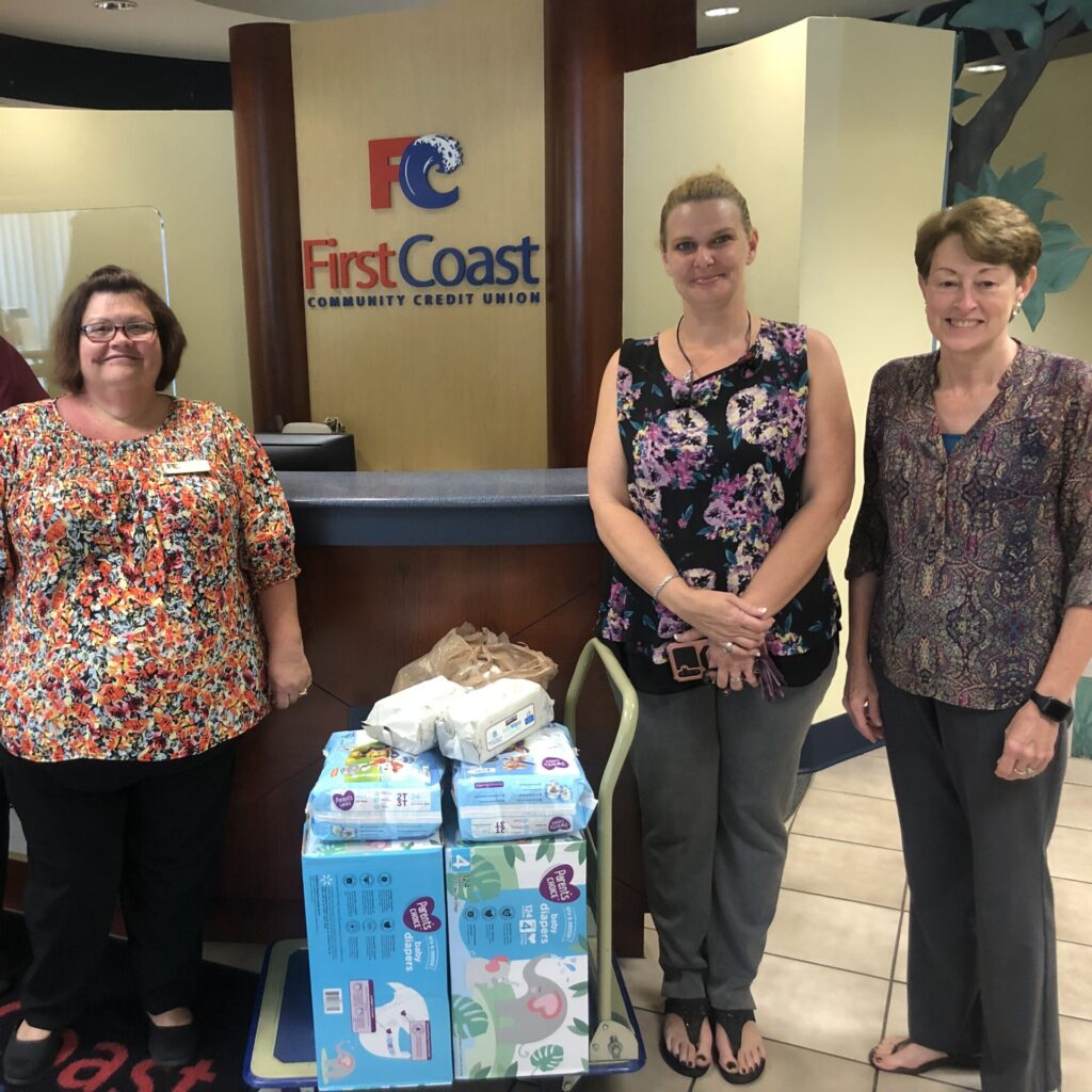 Three women posing for picture with baby diapers