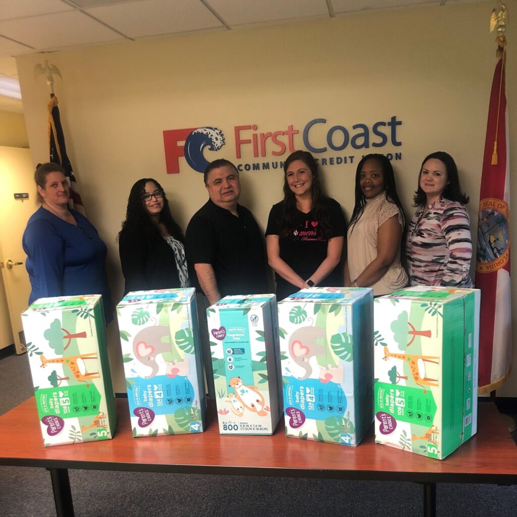 Group of people standing behind boxes of baby diapers