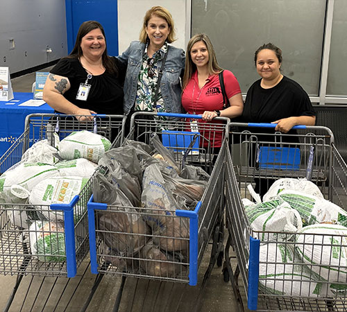 Four ladies standing behind grocery carts of turkeys